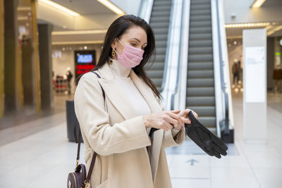 Woman wearing mask holding gloves at shopping mall