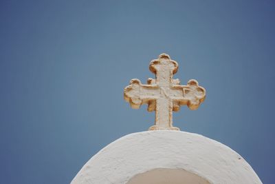 Low angle view of cross against building against clear blue sky