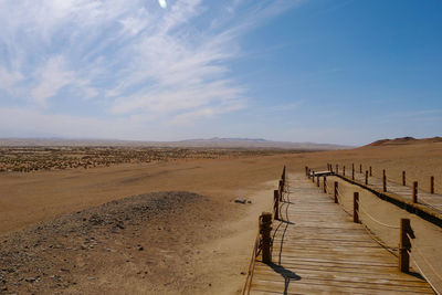 Wooden posts on sand against sky