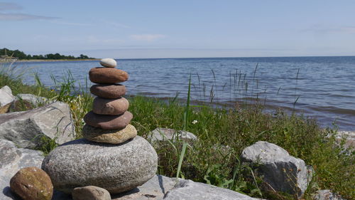 Stack of stones at seashore against sky