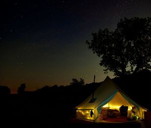 Silhouette of tent against sky at night