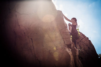 Man standing on rock against sky