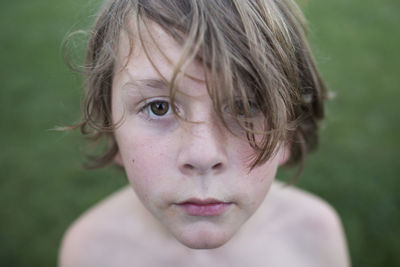 Close up of young boy with long hair, brown eyes, and messy face