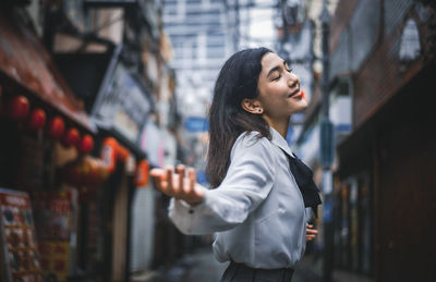 Side view of young woman standing in city