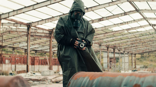 Man with gas mask photographs the radioactive barrels