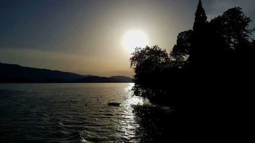 Silhouette of trees and sea against sky during sunset