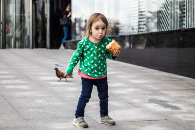 Portrait of cute girl standing on footpath