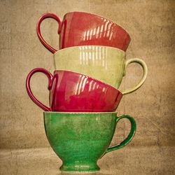 Close-up of stacked colorful tea cups by brown paper