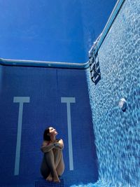 High angle view of woman standing by swimming pool