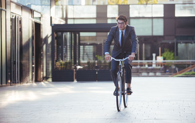 Full length portrait of young man riding horse in city