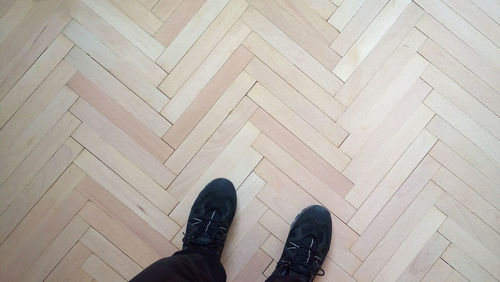 Low section of man standing on hardwood floor