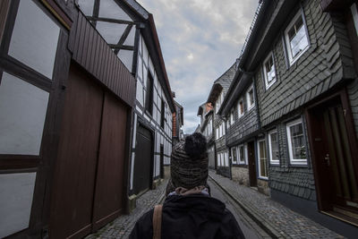 Rear view of a person along built structures