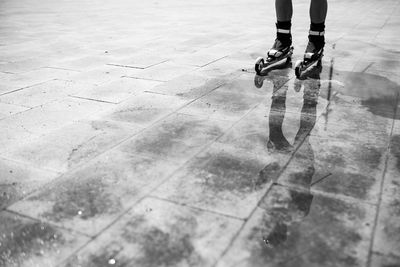 Low section of person inline skating on wet tiled floor