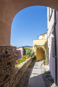 Alley amidst buildings against blue sky