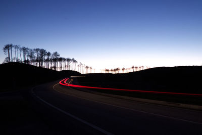 Light trails on highway against sky at night