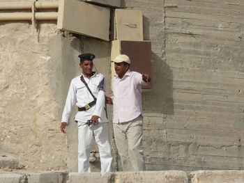 Men having discussion while standing against wall outdoors