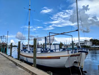 Boats moored at harbor against sky