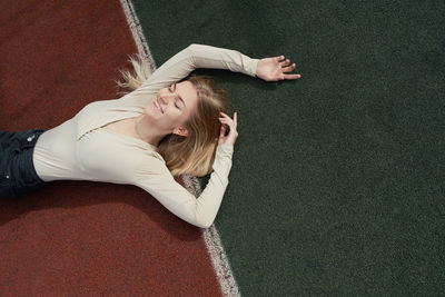 Smiling young woman lying on sports court