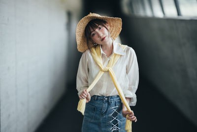 Portrait of young woman standing against wall