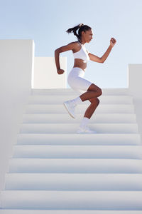 Full length of young woman jumping against wall