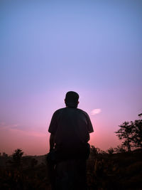 Rear view of silhouette man looking at sunset