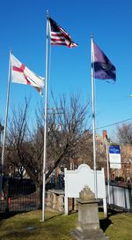 Low angle view of flags at cemetery against blue sky