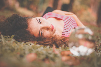 Close-up portrait of young woman lying on grass