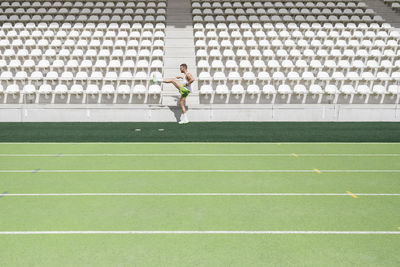 Athlete practicing warm up exercise at sports field on sunny day