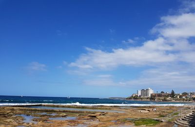 Scenic view of sea by buildings against blue sky