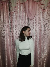Young woman looking away while standing in curtain