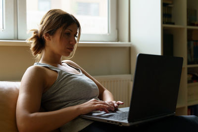 Young woman using mobile phone at home