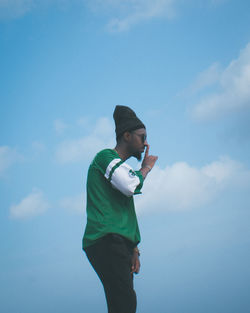 Low angle view of young man standing against sky