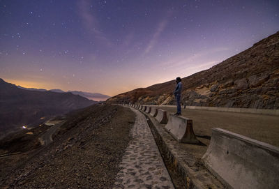 Side view of man standing on road at night