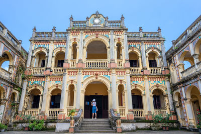 People walking in historic building against sky