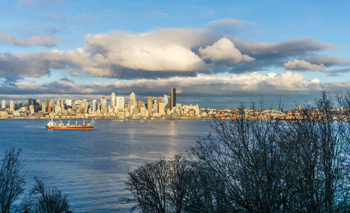 Clouds hover over the seattle skyline as a ship moves across elliott bay.