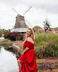 Portrait of smiling young woman standing against windmill