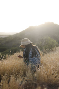 Rear view of woman sitting on grass against sky