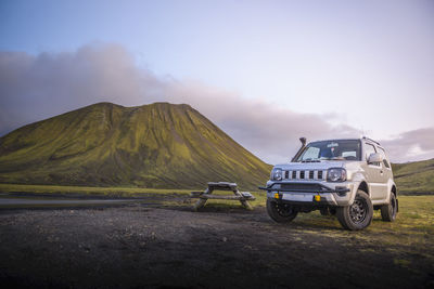 4x4 parked next to picnic table in front of mountain next to river