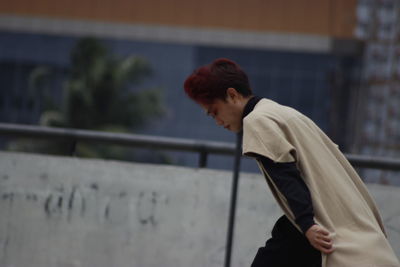 Side view of man leaning against railing