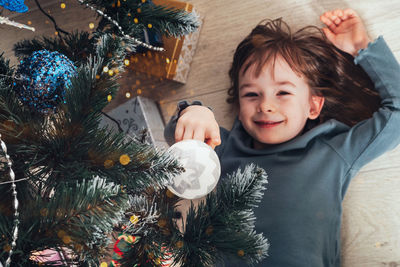 Happy child lies under the new year tree and touches the christmas tree toy. christmas mood.