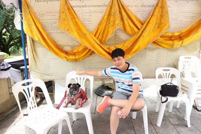 Portrait of mid adult woman with pug sitting on chairs