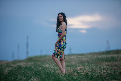 Young woman standing on field against sky