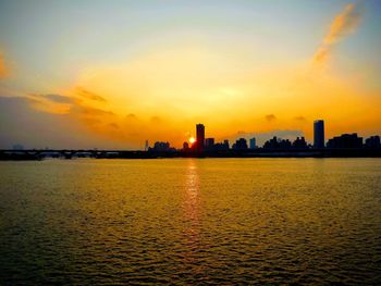 Scenic view of sea and buildings against sky during sunset