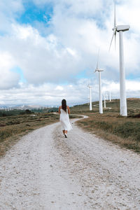 Rear view of woman walking on street against sky