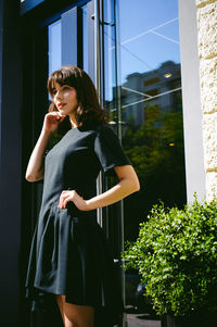 Beautiful young woman standing at entrance of building