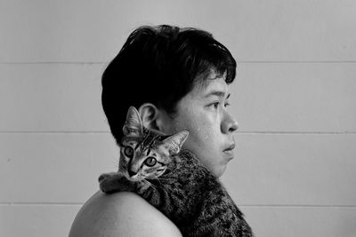 Portrait of woman with cat against wall