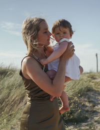 Mother and daughter standing on land against sky