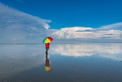 Person standing on beach against blue sky