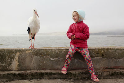 Full length of woman by seagulls on sea shore