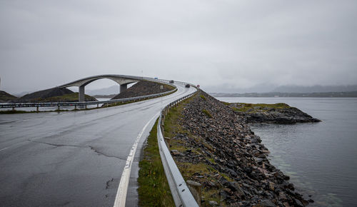 Bridge over road by sea against sky